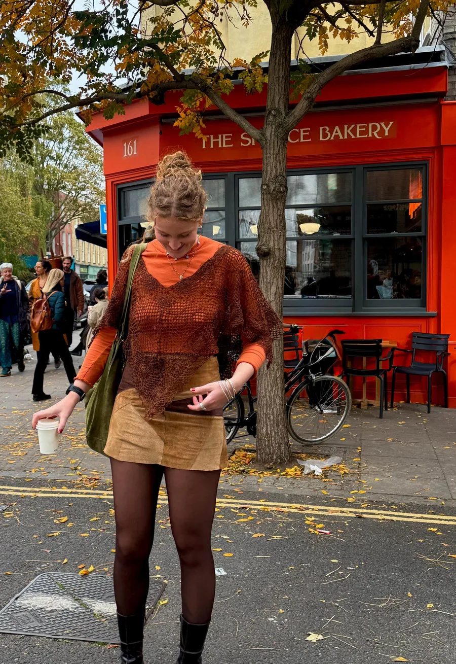 Brown Clover Poncho styled over an orange top and skirt outdoors