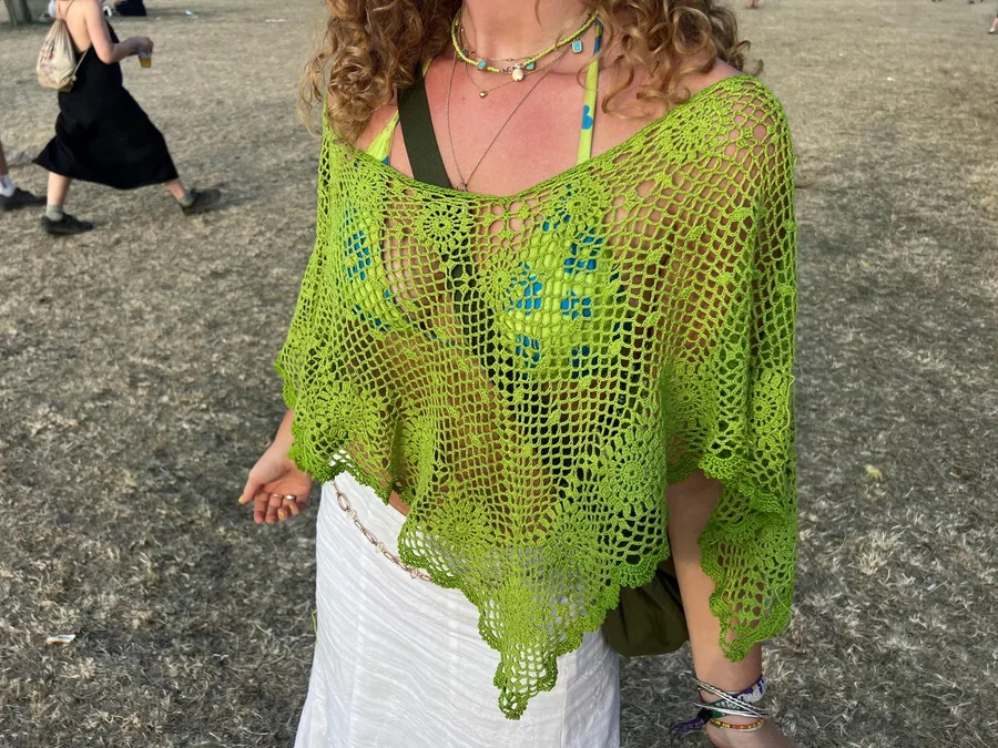 Lime green openwork Clover Poncho worn over a patterned top and white skirt