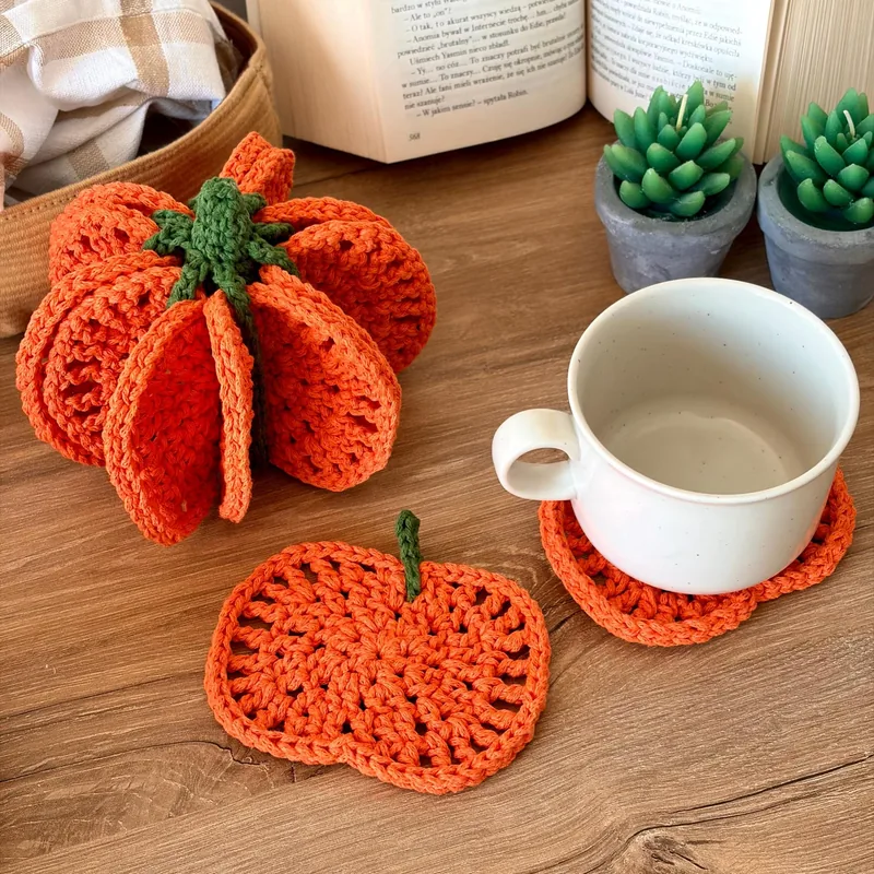 Orange crochet pumpkin made from coasters beside a mug resting on a matching pumpkin coaster