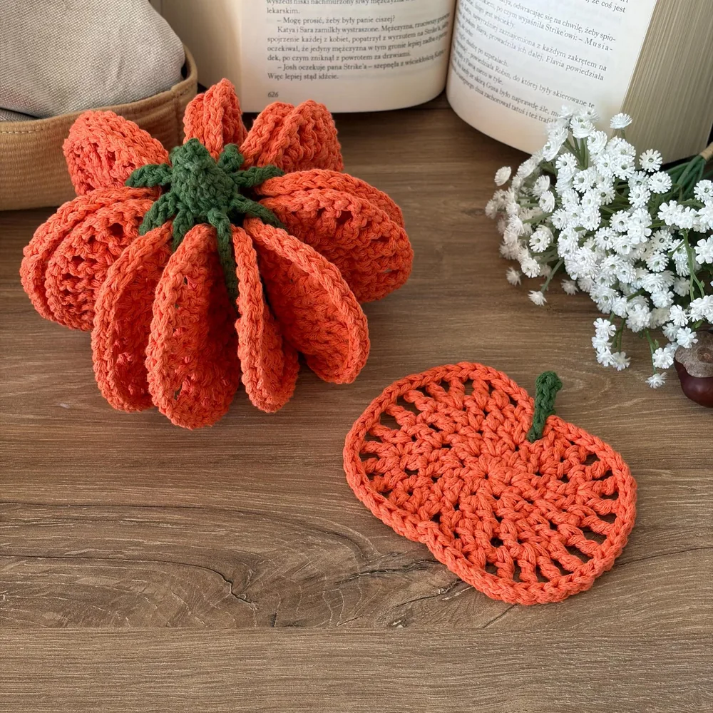 An assembled orange crochet pumpkin beside a separate pumpkin-shaped coaster