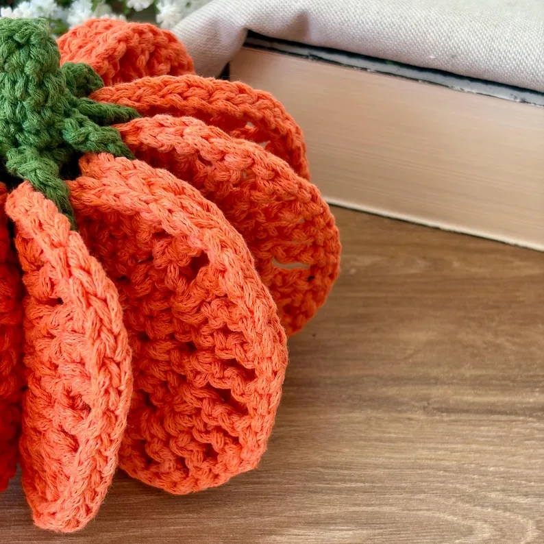 Close view of the folded orange crochet coaster pieces that form the pumpkin