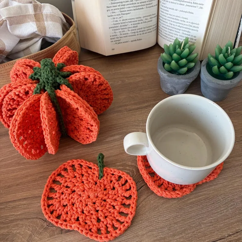 Orange crochet pumpkin assembled beside its matching coaster and a white mug