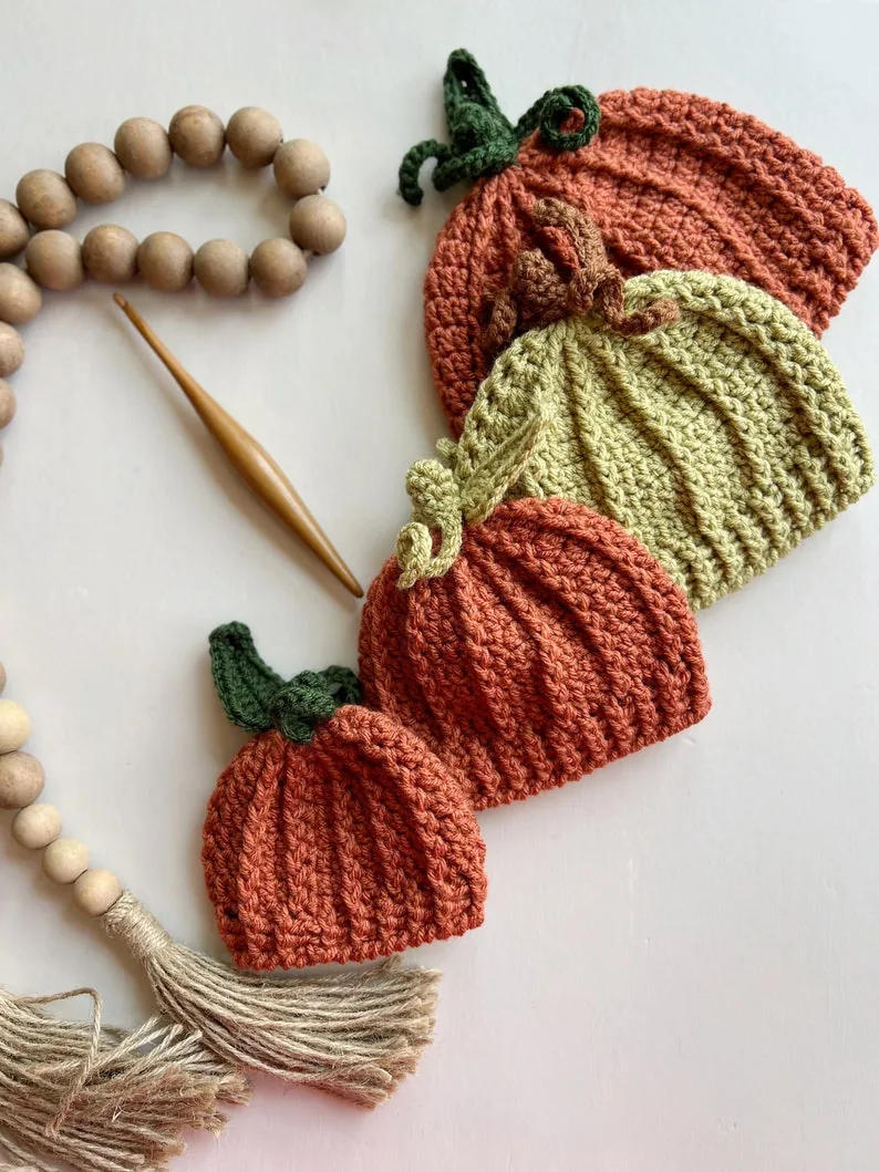 Four crocheted pumpkin beanies in different sizes and autumn colors