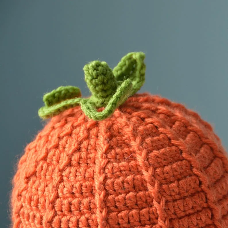 Close-up of the orange pumpkin beanie's raised crochet texture and green stem