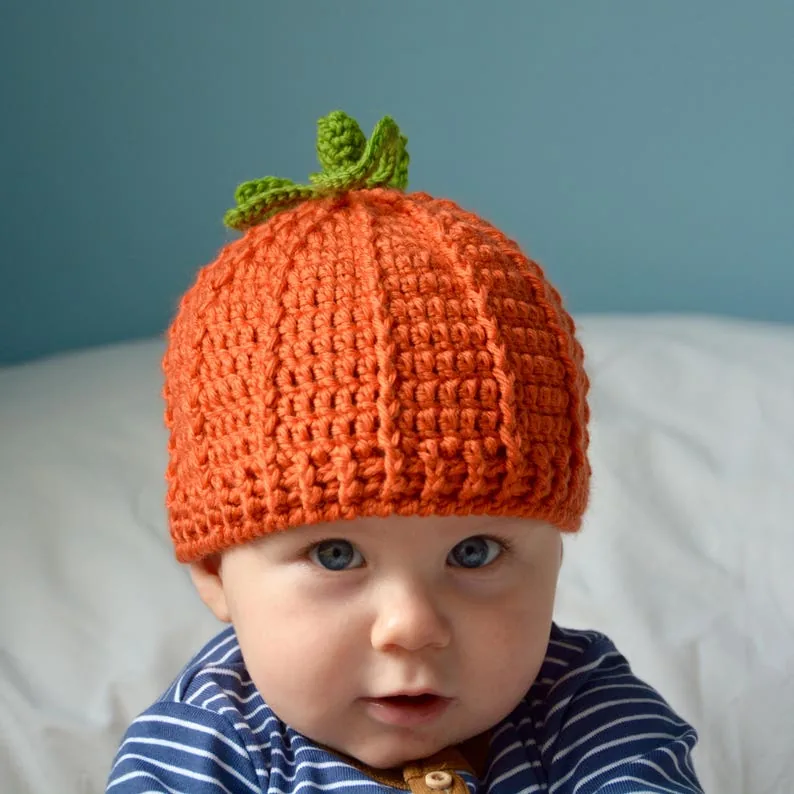 Baby wearing the orange crocheted pumpkin hat with a green stem