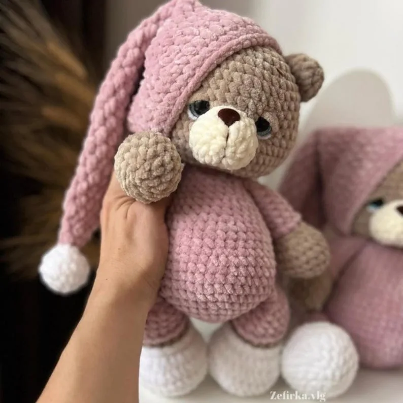 Pink crochet teddy bear with a long sleeping cap and white slippers